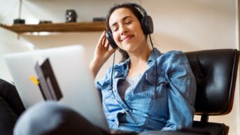 a woman wearing headphones sitting in front of a laptop computer
