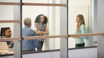 two women and a man standing in front of a whiteboard
