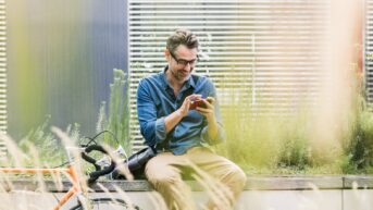 a man sitting on a bench looking at his cell phone