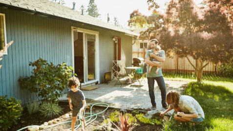 a man holding a baby while standing in a garden