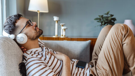 a man laying on a couch wearing headphones