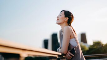 a woman standing on a ledge with her eyes closed