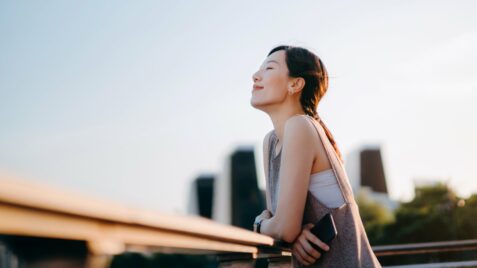 a woman standing on a ledge with her eyes closed
