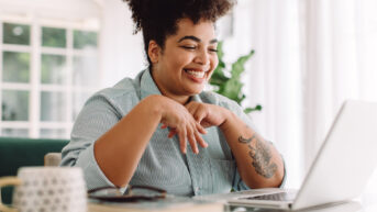 a woman sitting at a desk with her hands on her chest