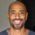 a bald man with a necklace on his neck