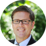 a man wearing glasses and a suit smiling