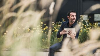 a man sitting on a bench holding a tablet
