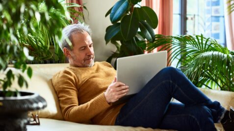 a man sitting on a couch using a laptop computer