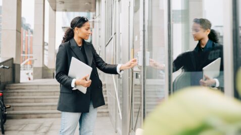 a woman in a business suit opening a door