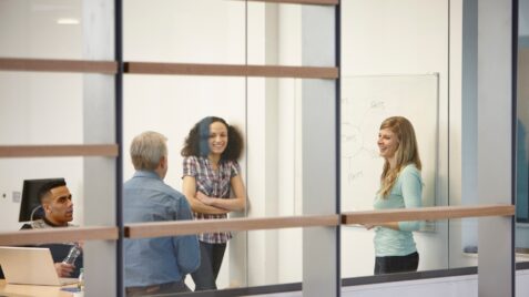 a group of people standing in front of a whiteboard