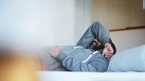 a man laying on top of a couch with his head in his hands