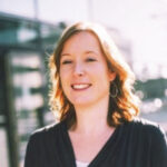 a woman with red hair and earrings smiles at the camera