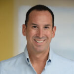 a man in a blue shirt smiling at the camera