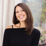 a smiling woman in front of a window