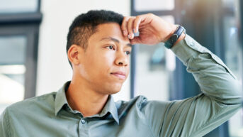 a young man is holding his head with one hand