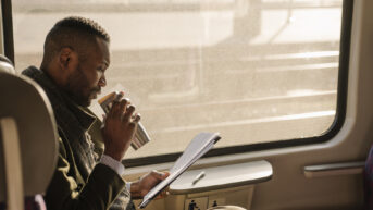 a man sitting on a bus drinking coffee