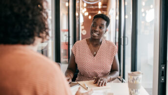 a woman sitting at a table in front of a window