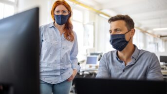 a man and woman wearing face masks in an office