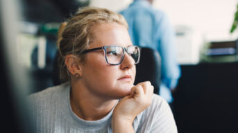 a woman wearing glasses sitting at a desk