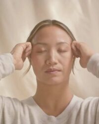 a woman is holding her head with both hands