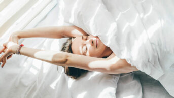 a woman laying in bed under a white sheet