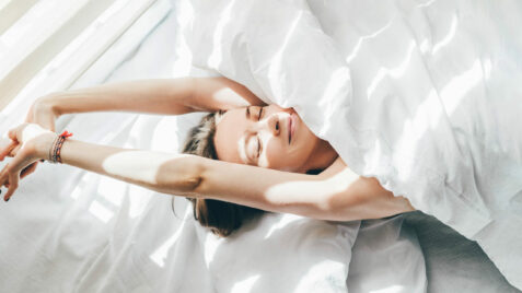 a woman laying in bed under a white sheet