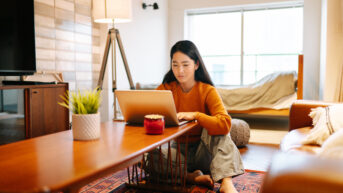 a woman sitting on the floor using a laptop computer