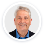 a man in a blue shirt and black jacket smiling