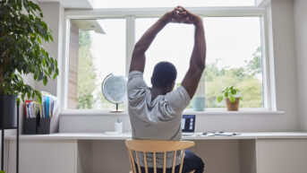 a man sitting at a desk with his arms in the air