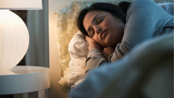 a woman laying in bed next to a lamp