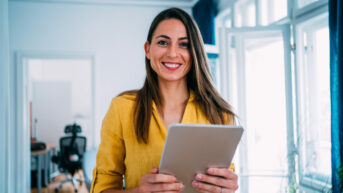 a smiling woman holding a tablet in her hands