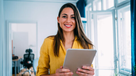 a smiling woman holding a tablet in her hands