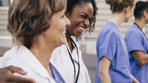 three women in scrubs are smiling together