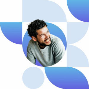 a man with curly hair smiling and wearing a grey sweater