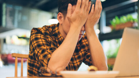 a man sitting at a table with his hands covering his face