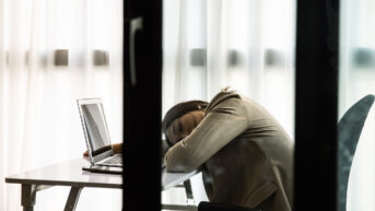 a woman sitting at a desk with her head in her hands