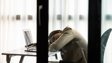 a woman sitting at a desk with her head in her hands