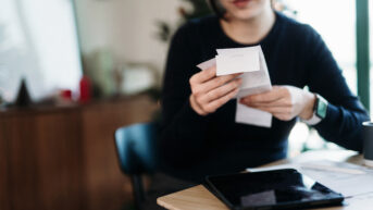 a woman sitting at a table holding some papers