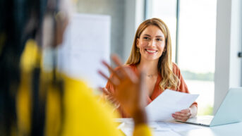a woman sitting at a table with papers in front of her