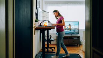 a woman standing at a desk on a treadmill
