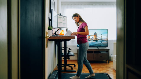 a woman standing at a desk on a treadmill