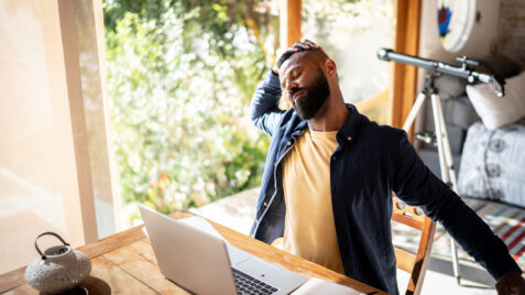 a man taking a micro break at his desk, stretching