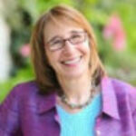 a smiling woman in a purple jacket and blue shirt