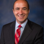 a man in a suit and tie smiling for a picture