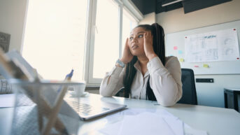 a woman sitting at a desk in front of a laptop computer