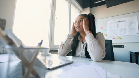 a woman sitting at a desk in front of a laptop computer