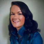 a woman in a denim jacket smiling at the camera