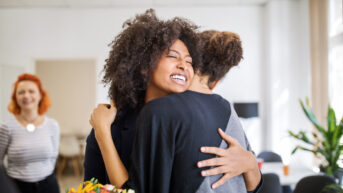 Employee gratitude. Woman hugging coworker in gesture of appreciation.
