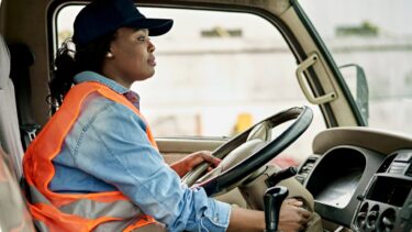 a woman in an orange vest driving a truck