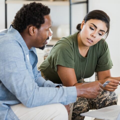 a man and a woman sitting on a couch looking at a laptop